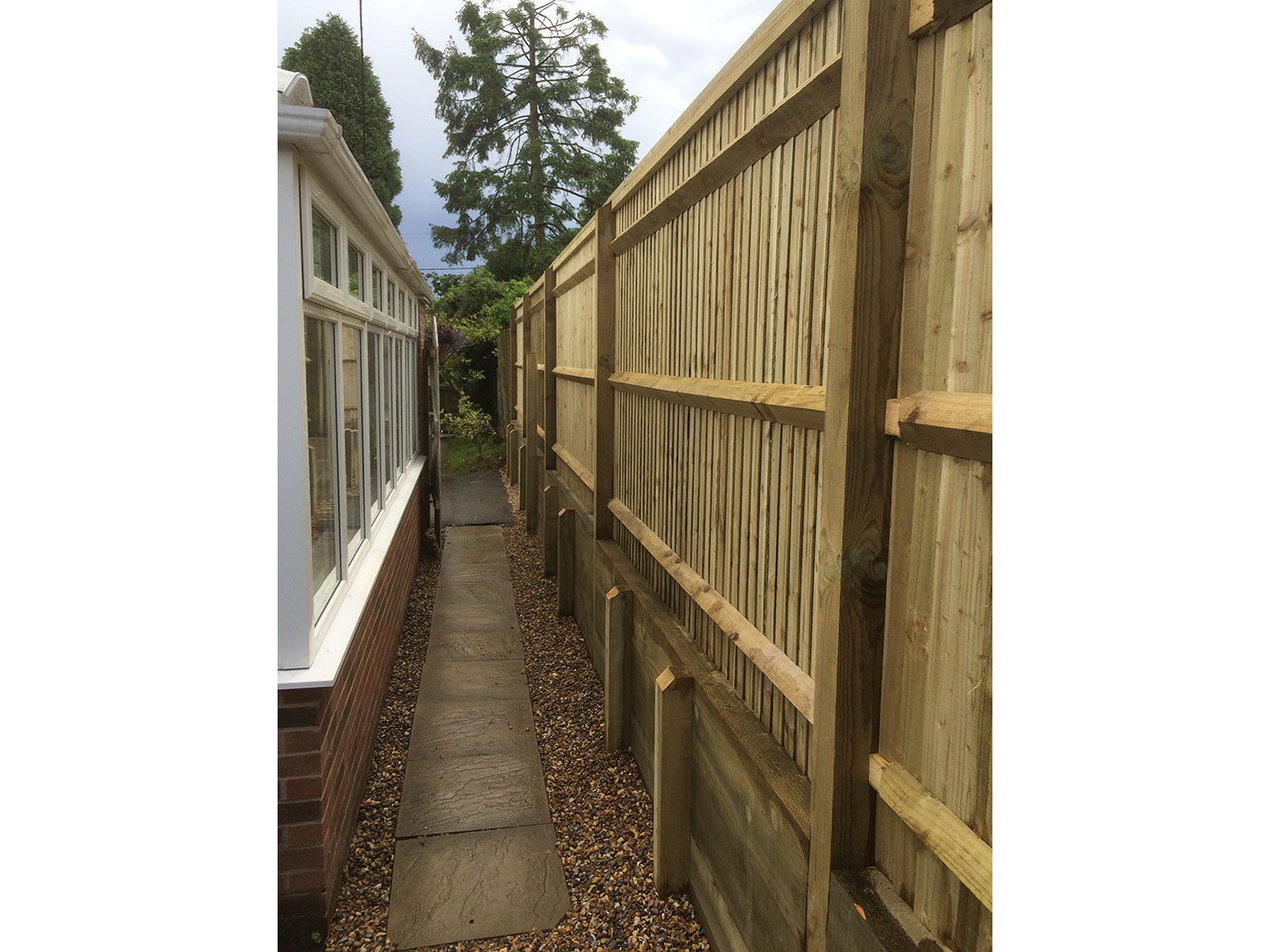 Closed board fence with sleeper retaining wall by Vincent Fencing