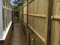 Closed board fence with sleeper retaining wall by Vincent Fencing
